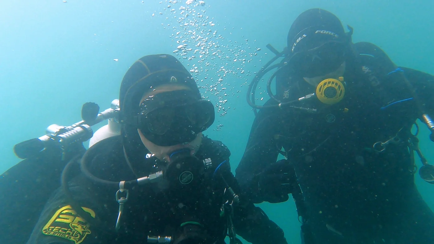 Zwei Taucher in technischer Konfiguration im kalten Grünwasser